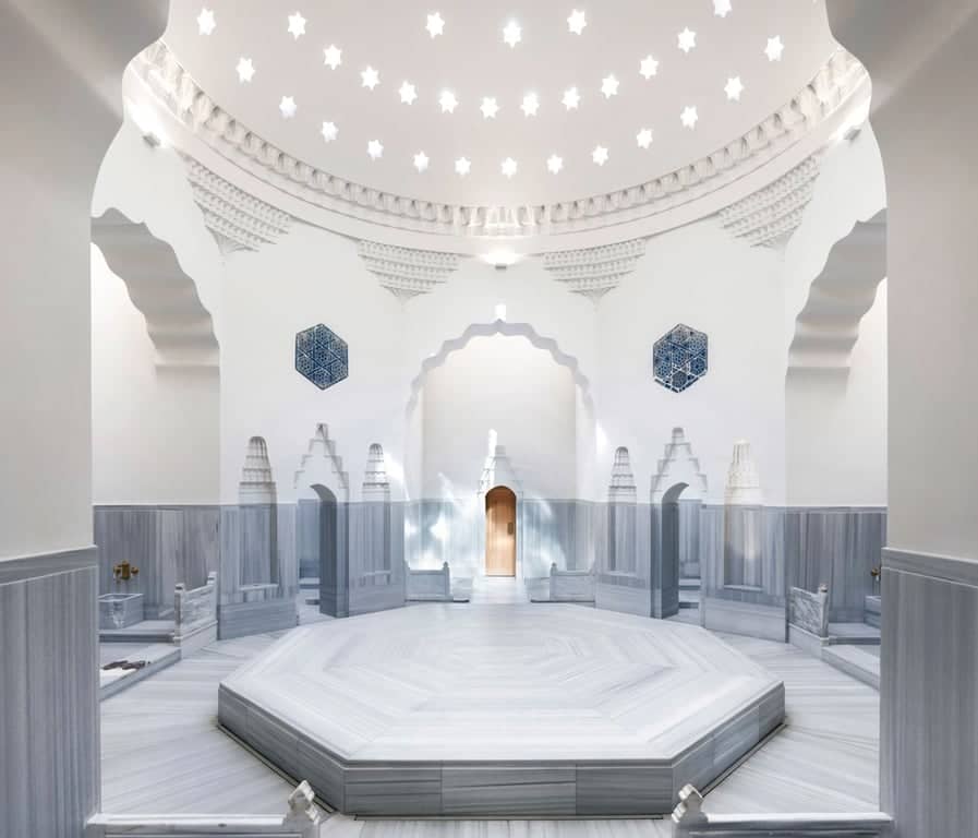 Spacious white marble hammam chamber with central heated stone platform