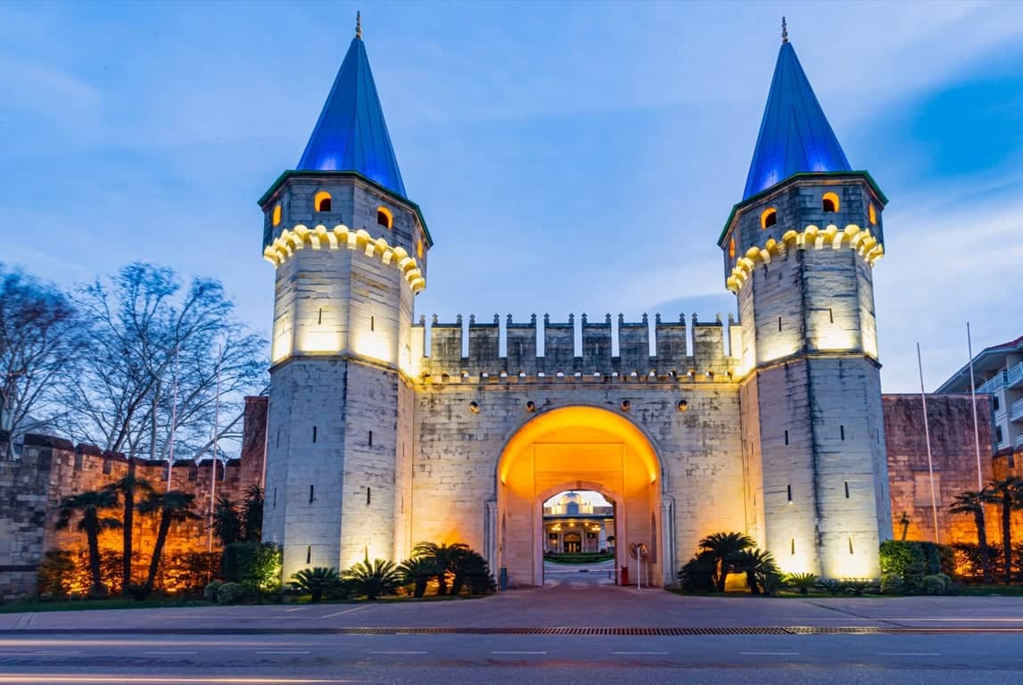Topkapi Palace Imperial Gate illuminated in the evening, people entering