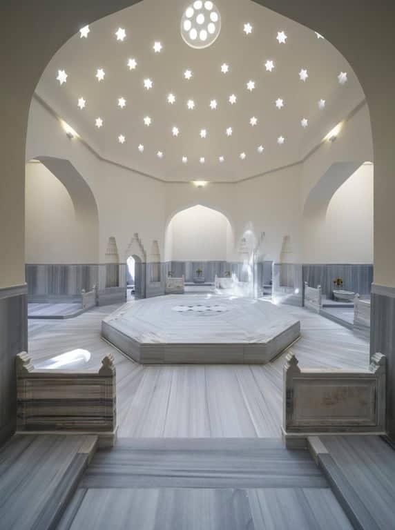 Bright hammam interior with central marble slab and star-patterned ceiling