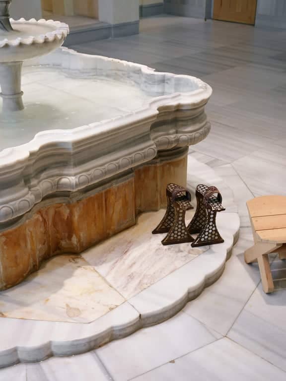 Marble water basin with flowing tap and traditional hammam accessories